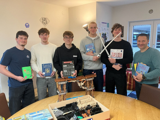 Gruppenfoto der Seminarkursteilnehmer mit Lehrkraft Martin Rathgeb (rechts) im KI-makerspace; Teilnehmer halten Bücher in den Händen