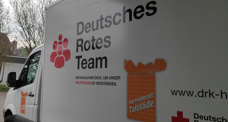 Lieferwagen des Tafelladens Herrenberg, groß zu sehen ist das Logo des Tafelladens (Mitte) und des deutschen Roten Teams (links)n